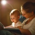 Mom reading to her baby in bed with a night light.