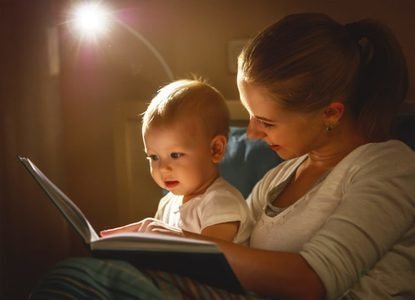 Mom reading to her baby in bed with a night light.