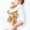 Sleeping Baby sucking its thumb holding a Teddy Bear