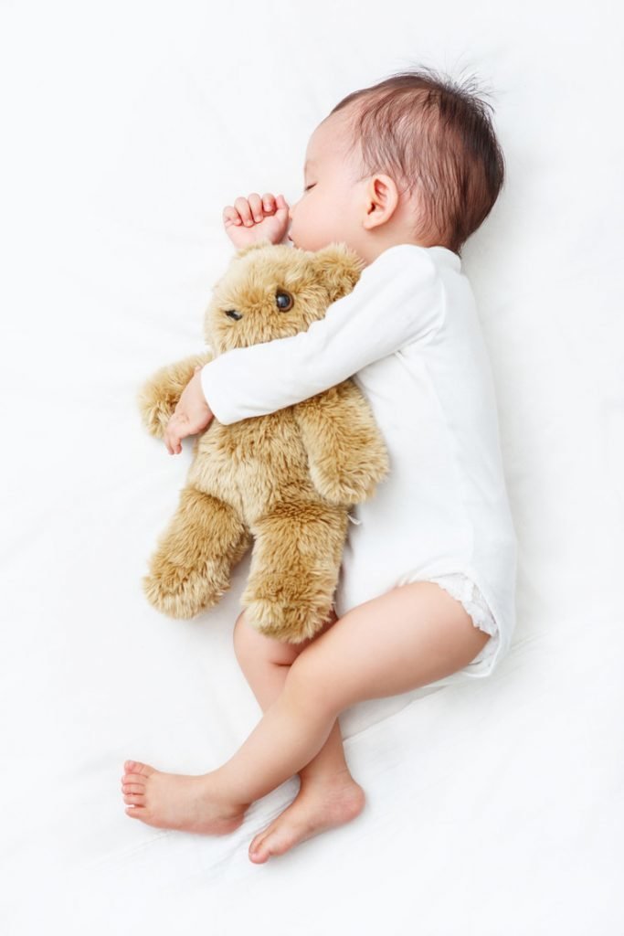 Sleeping Baby sucking its thumb holding a Teddy Bear