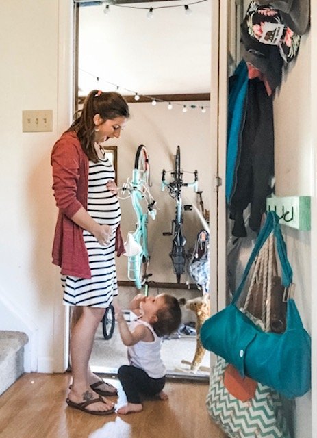 A pregnant mother standing in a doorway with her toddler.