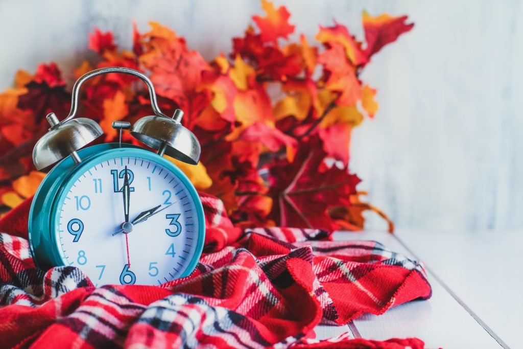 Daylight Savings Time Concept. Set Your Clocks Back With This Retro Beautiful Alarm Clocks Set To 2 Am Over Rustic White Background With Red Plaid Scarf And Autumn Leaves. Free Space For Text.