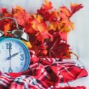 Daylight Savings Time Concept. Set Your Clocks Back With This Retro Beautiful Alarm Clocks Set To 2 Am Over Rustic White Background With Red Plaid Scarf And Autumn Leaves. Free Space For Text.