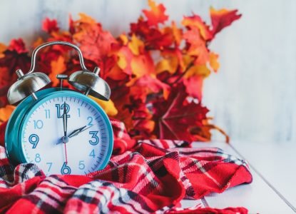 Daylight Savings Time Concept. Set Your Clocks Back With This Retro Beautiful Alarm Clocks Set To 2 Am Over Rustic White Background With Red Plaid Scarf And Autumn Leaves. Free Space For Text.